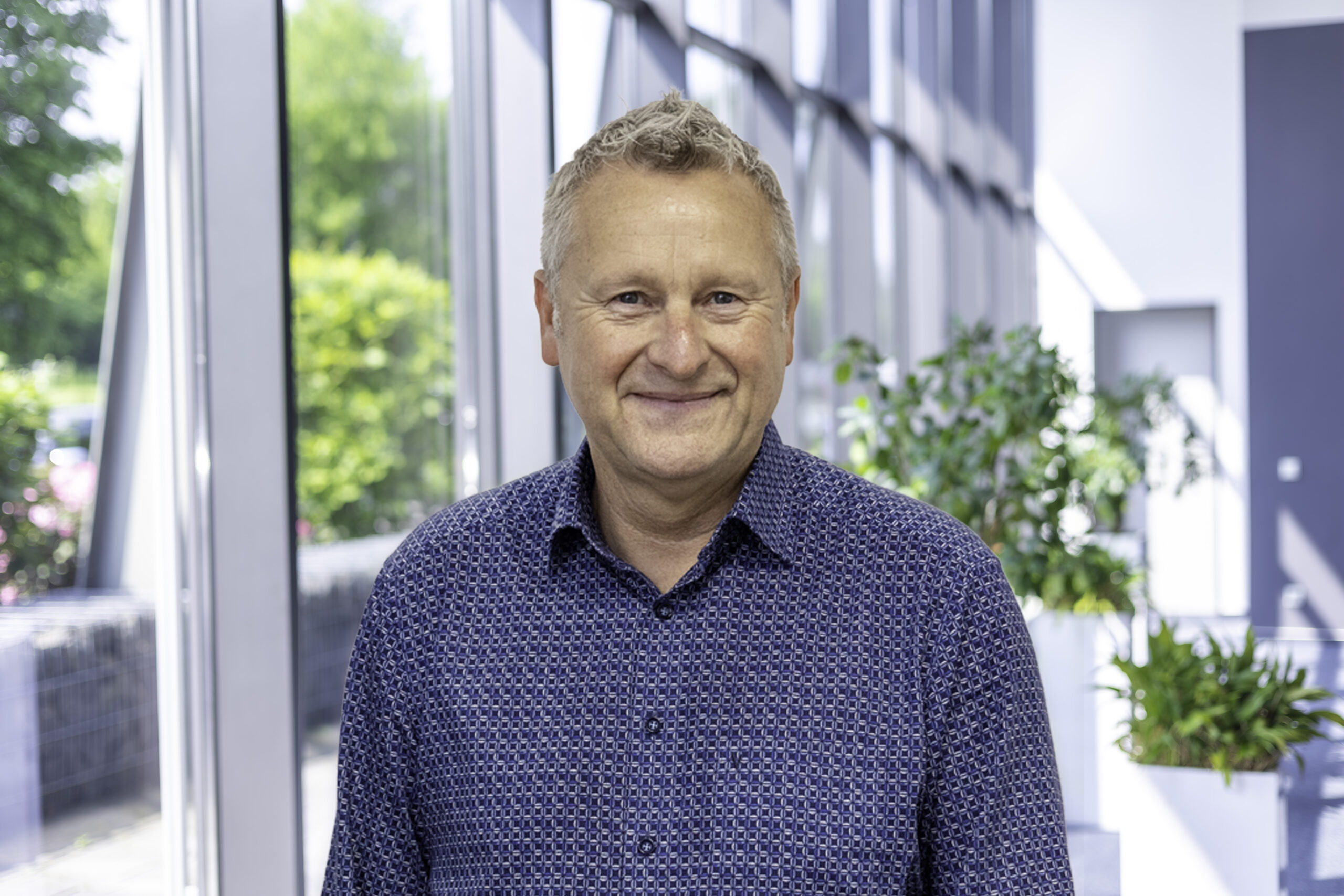 Joachim Kohn, Specialist for Connected Energy Solutions, in a foyer before a window front.