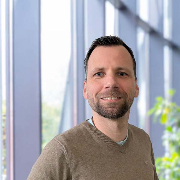 Portrait of Florian Euler in front of a window with blurred background.