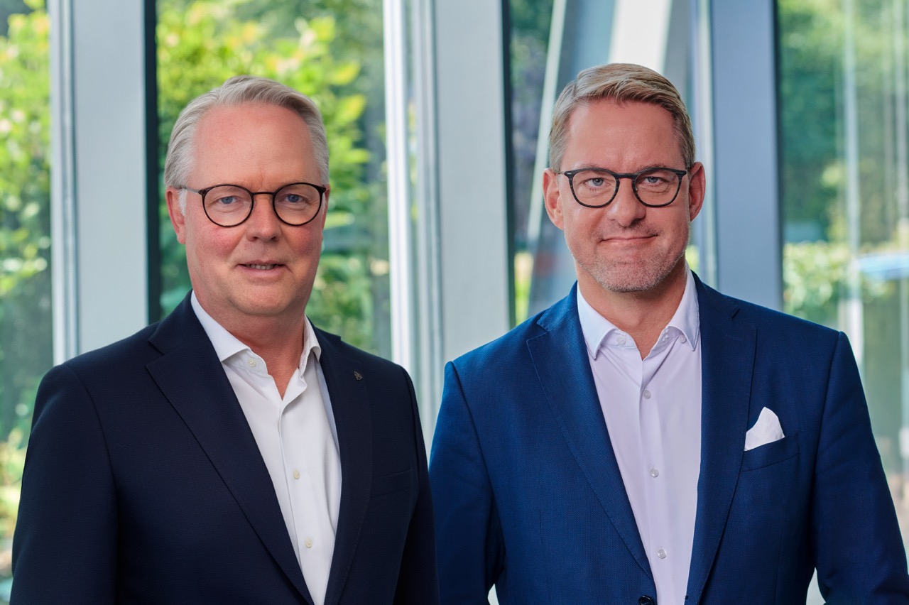 From left: Jürgen Deters and Tobias Schulz (management) in a bright foyer with large windows and plants in the background.