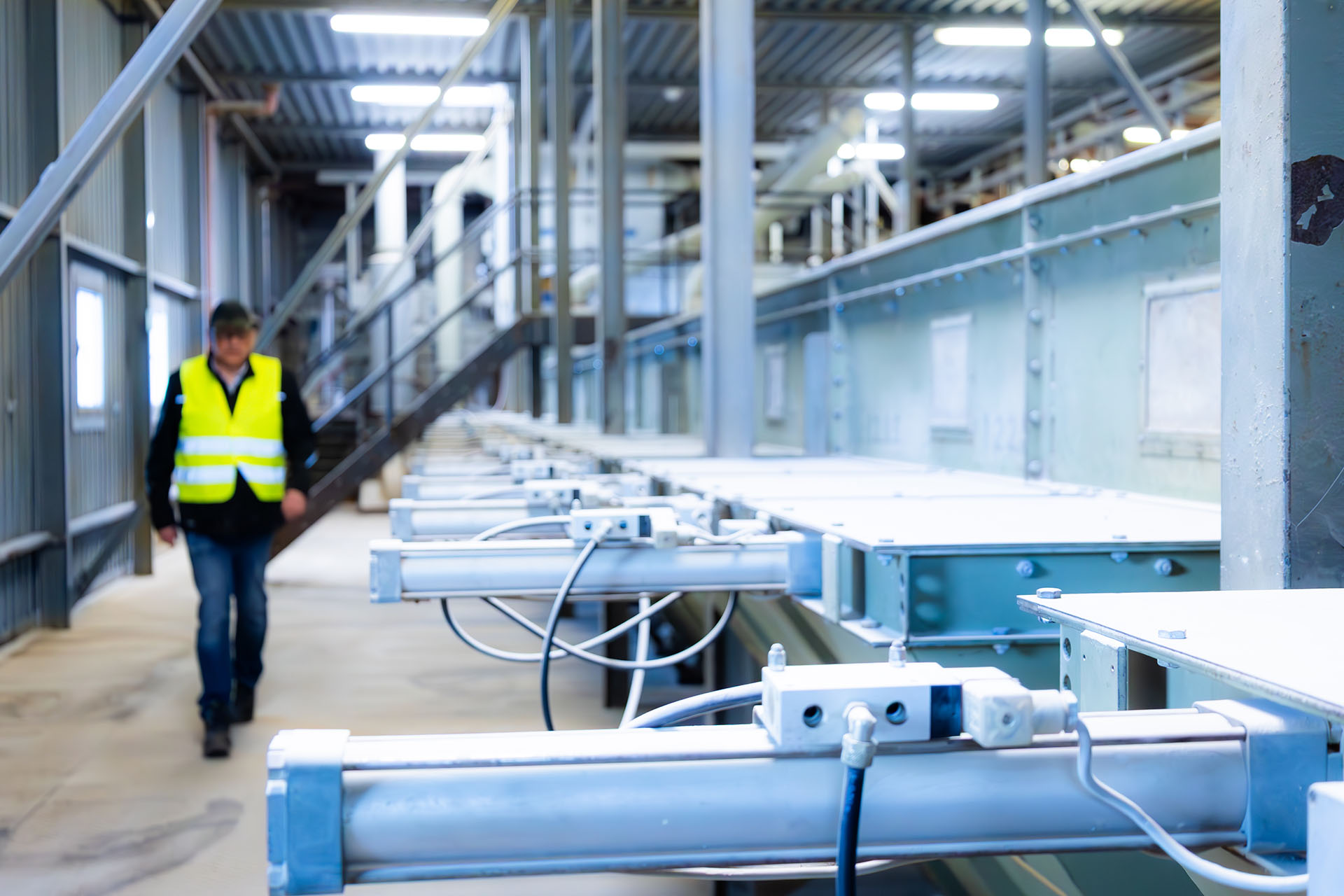Automated conveyor system with machinery and one person in the background.
