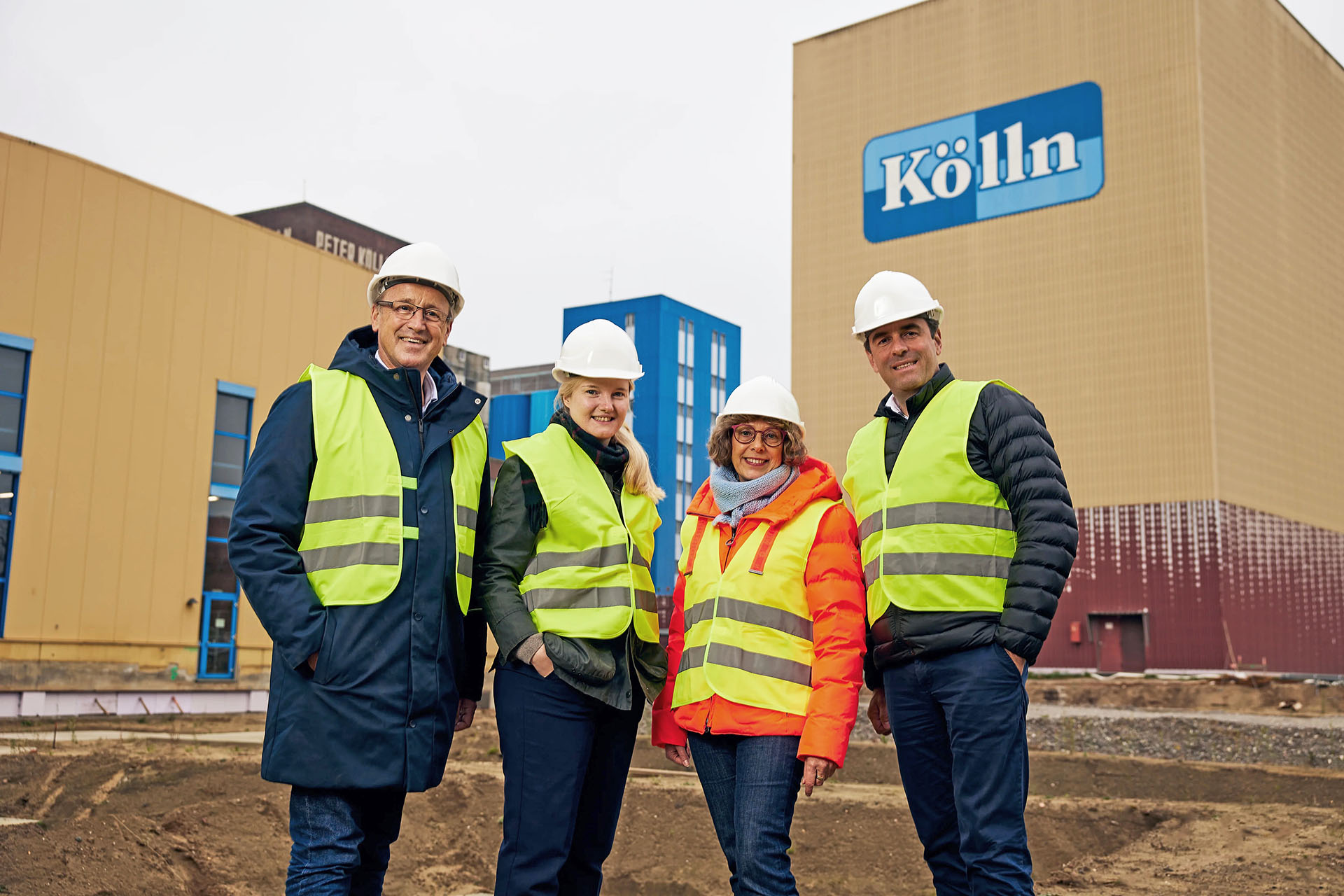 Four people wearing hard hats in front of Kölln's new production facility.